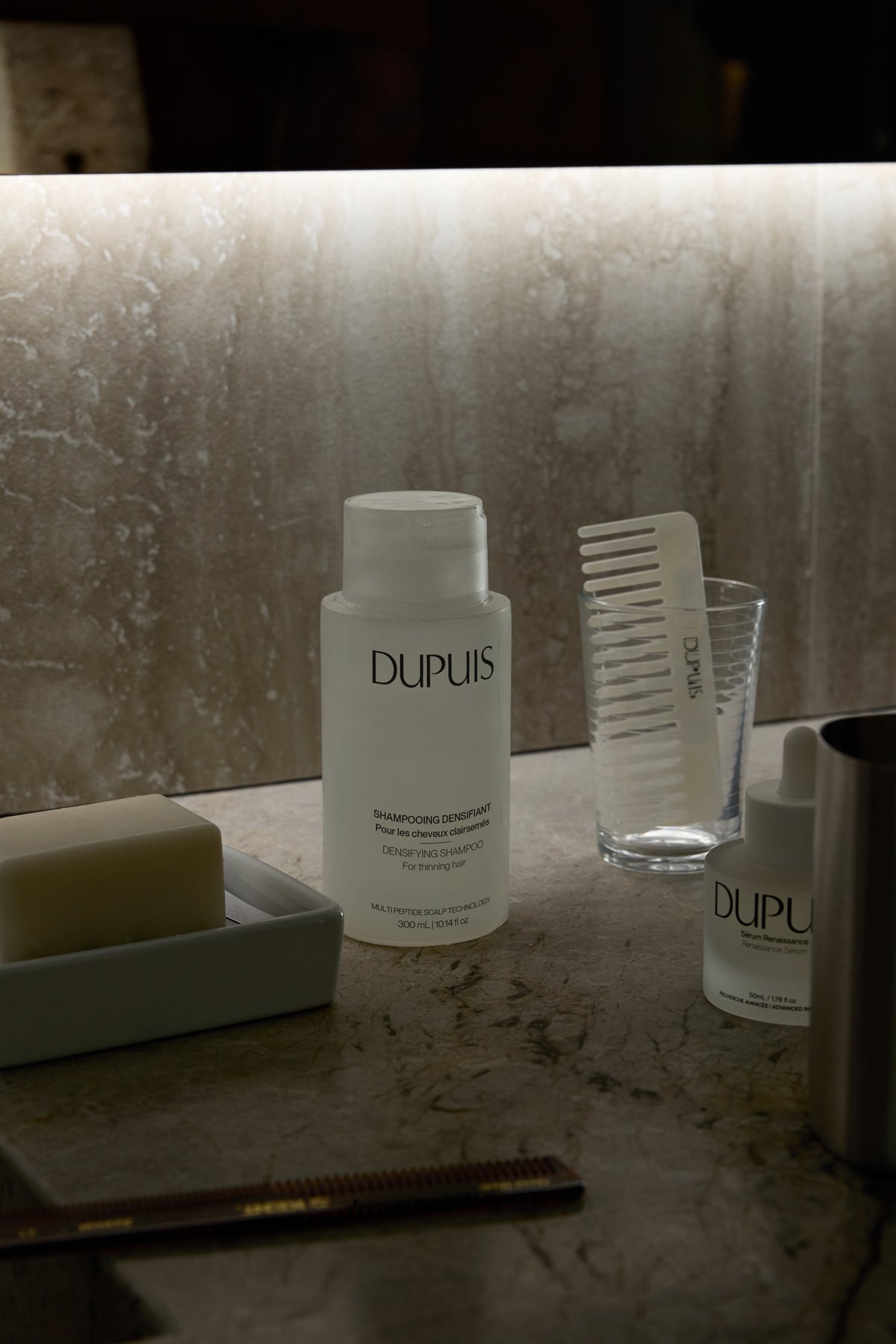 DUPUIS Densifying Shampoo and Renaissance Serum on a bathroom counter